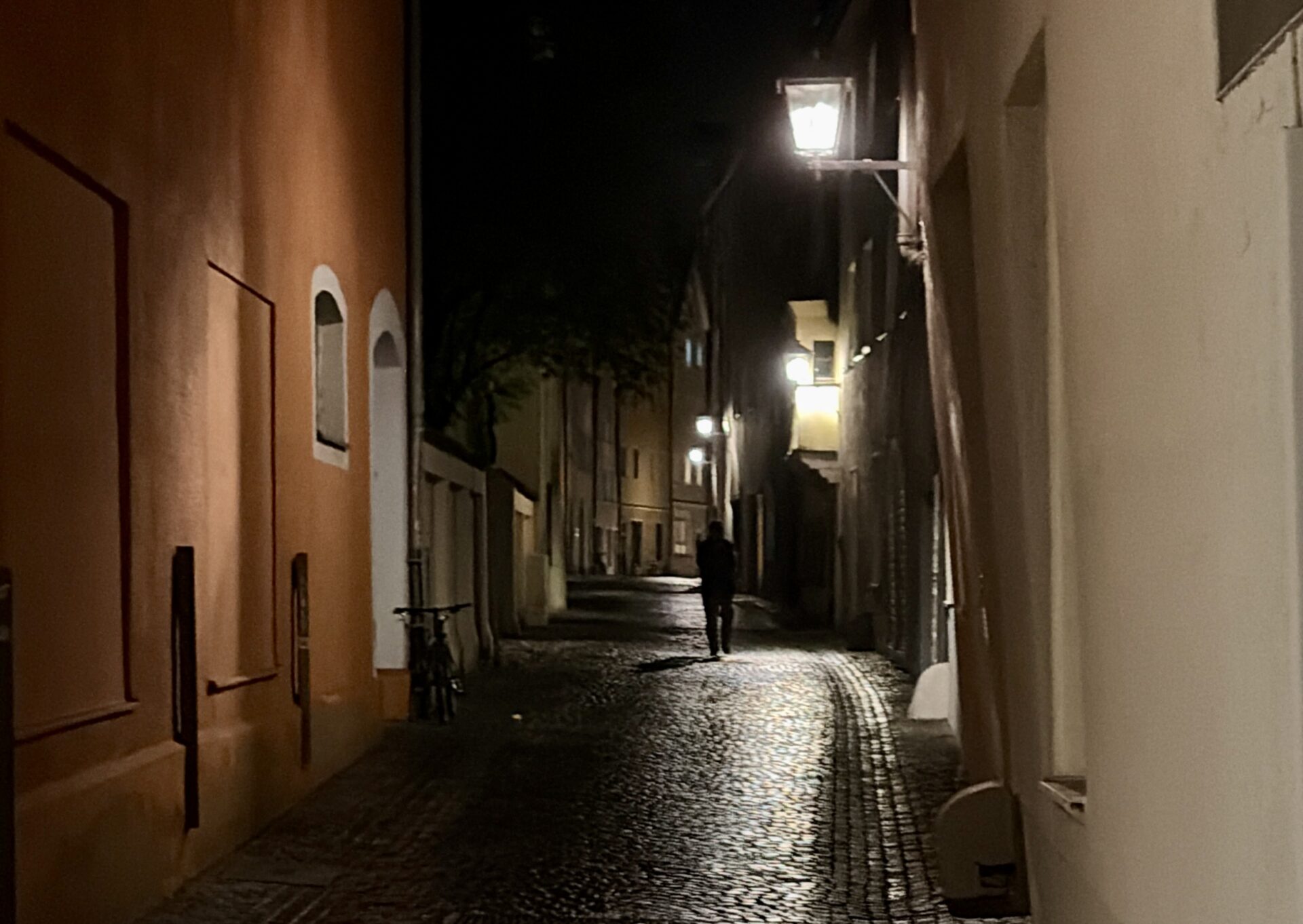 Nicht besser, nicht schlechter – nur anders 2 Dunkle Gasse mit historischen Gebäuden und Laternen, die den Weg beleuchten.