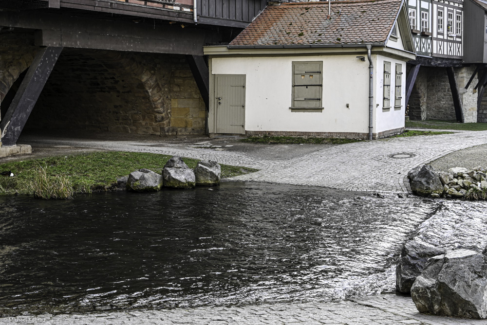 Erfahrungen und Fotos aus Erfurt 4 Erfurt – alte Furt über die Gera, graue Steine am Flussufer mit historischem Gebäudekomplex