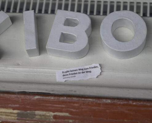 Erfurt: Weiße große 3D-Buchstaben liegen auf einem roten Sockel; darunter klebt ein Zitat von Mahatma Gandhi über Frieden, Blickfang durch Kontrast von Weiß und Rot