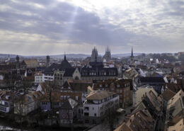 Erfurt Panorama Stadtansicht mit roten Dächern, Kirchtürmen und historischen Gebäudespitzen, sanfter Lichtstrahl durch Wolken über der Altstadt